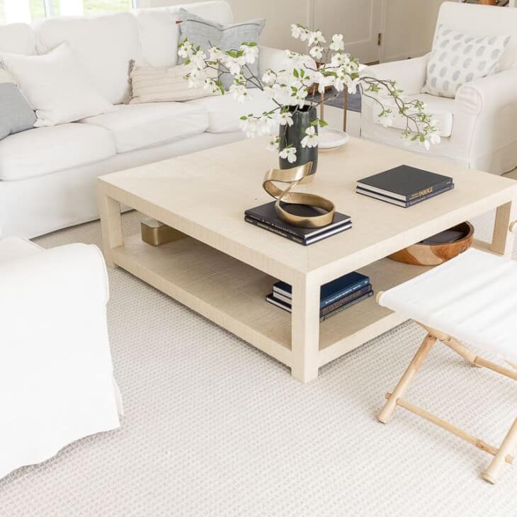 一个白色客厅，带有白色家具和拉菲亚咖啡桌。