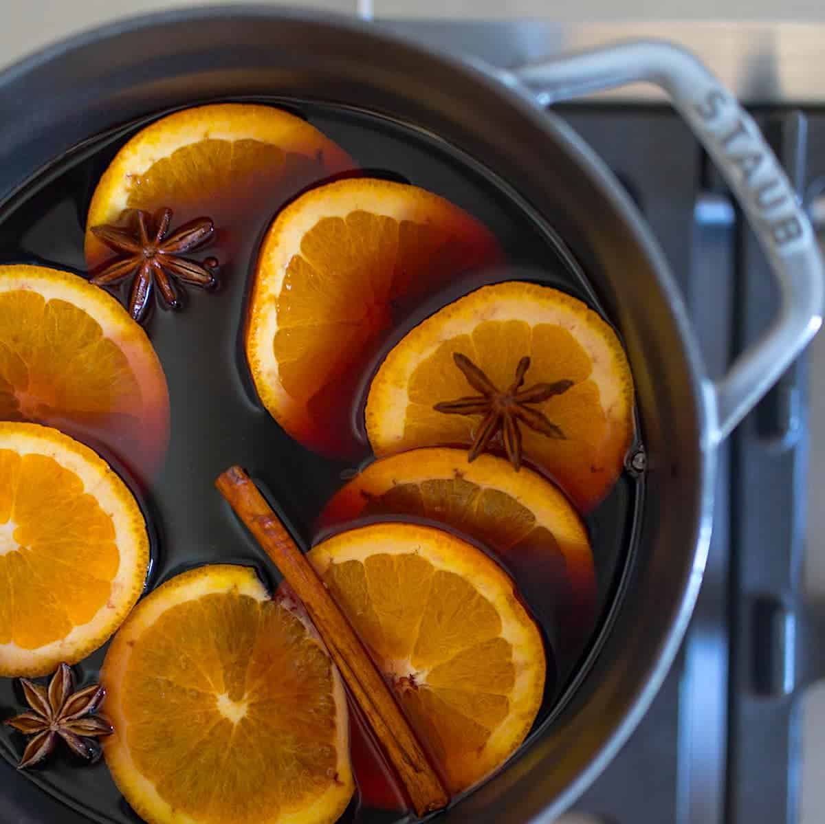 热红酒和热香料和橘子在炉子上的铸铁
