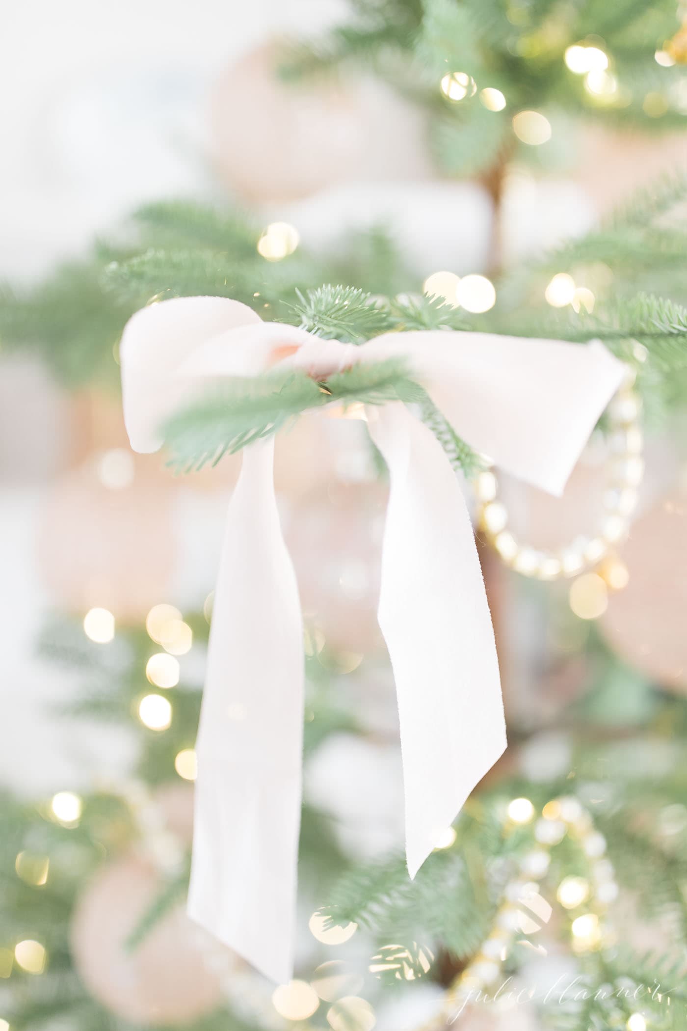 稀疏的圣诞树上系着柔软的粉色丝绸蝴蝶结