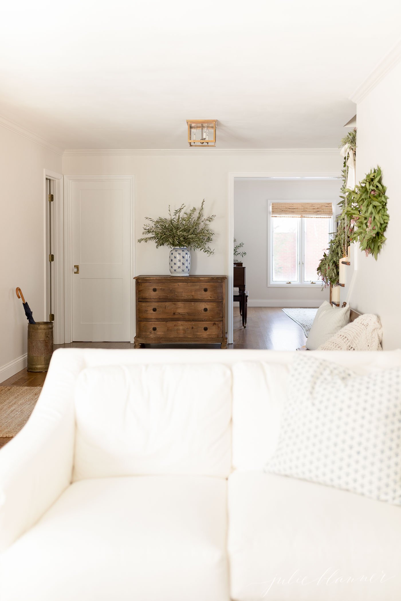 白色的客厅装饰着节日绿色植物和低调的储物容器。