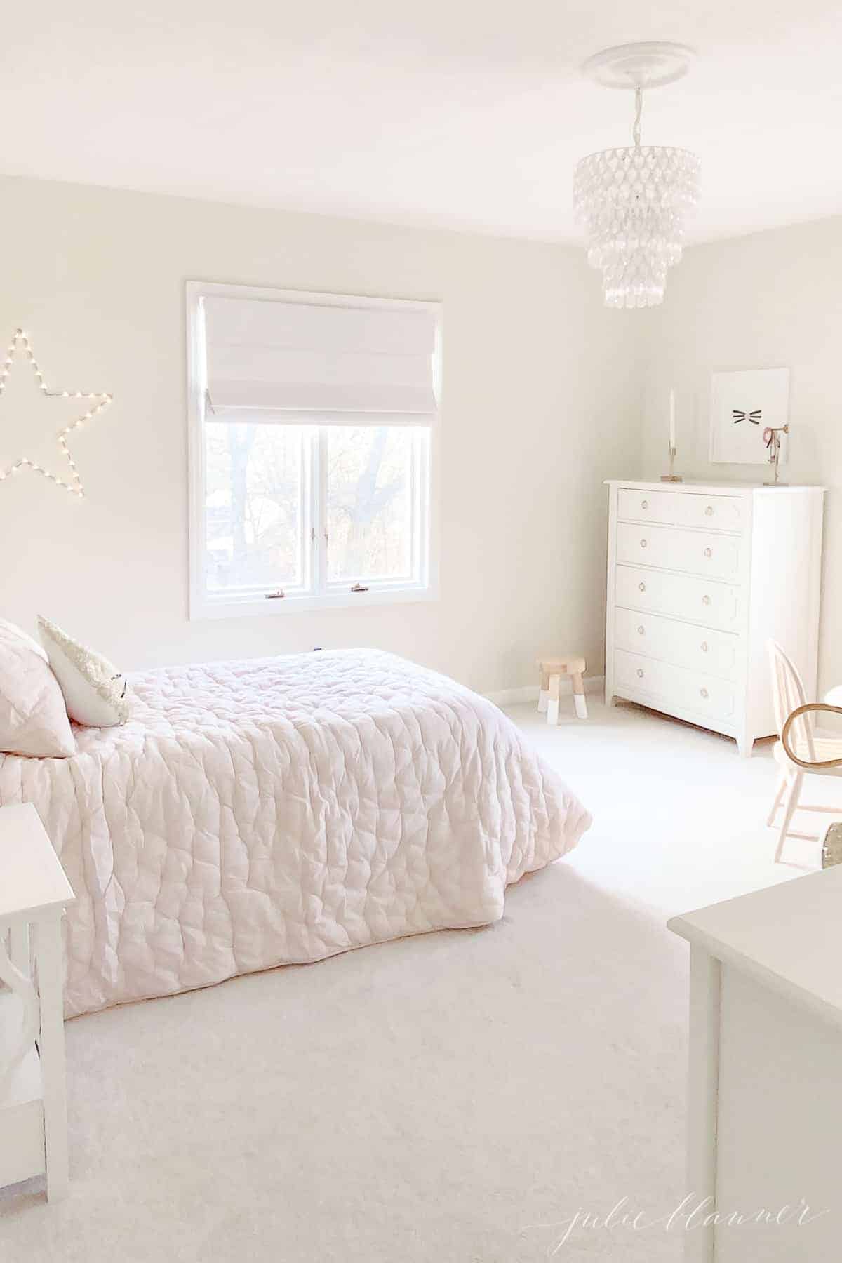粉红色和奶油色的卧室，白色的梳妆台和水晶灯