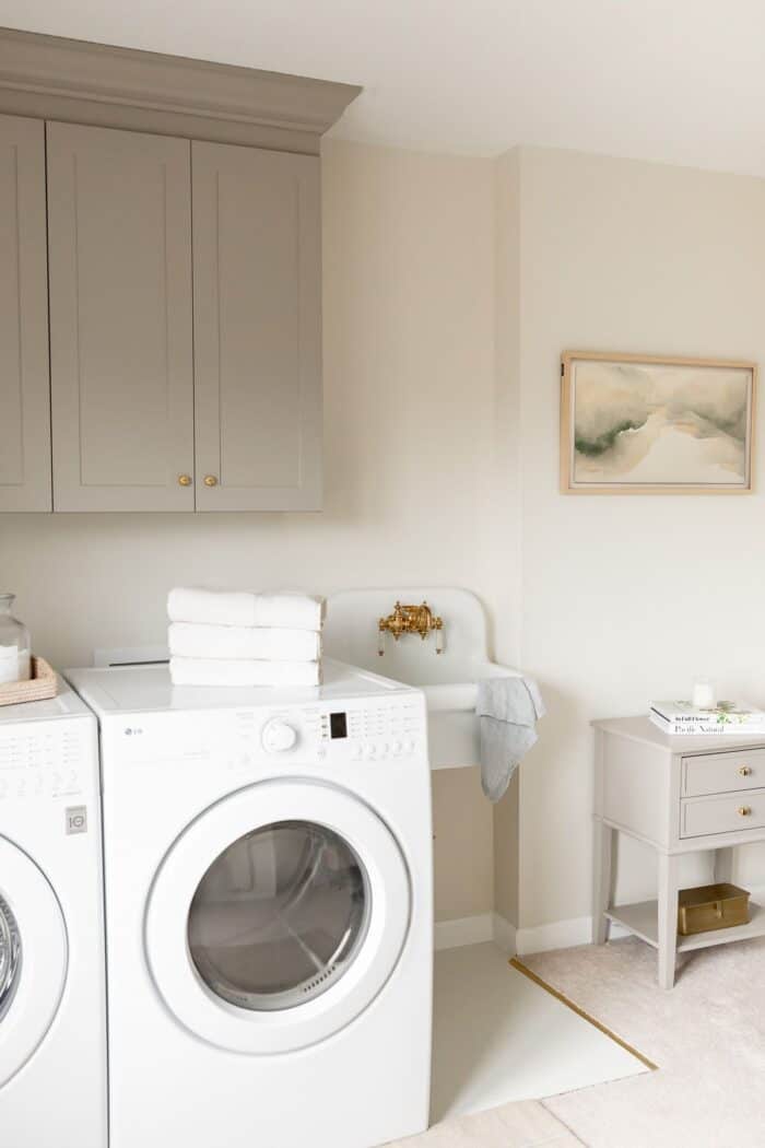 洗衣间里有一个白色的小水槽，一个边桌和几个用家具漆过的柜子