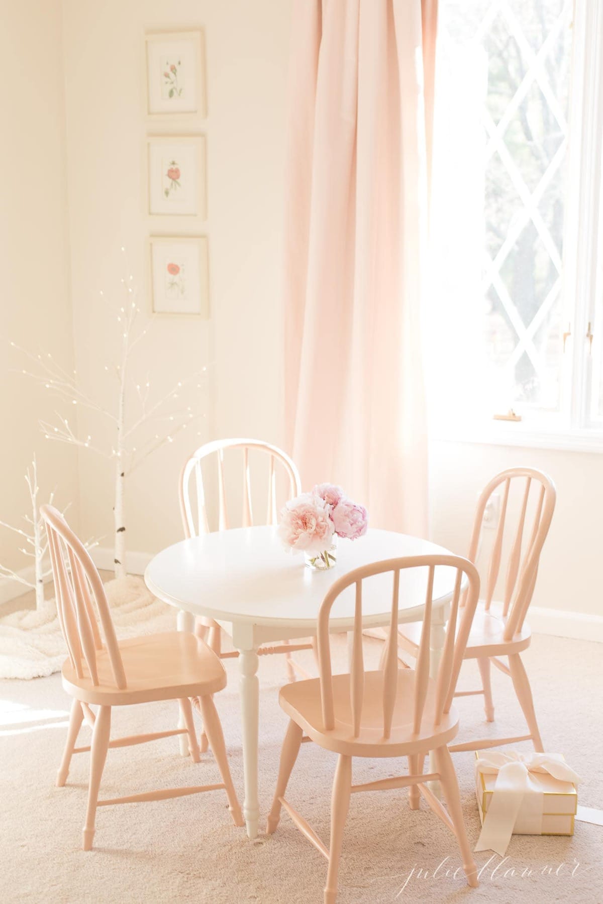一个白色的小女孩的卧室，有一张小圆桌和椅子，用新鲜的家具油漆。