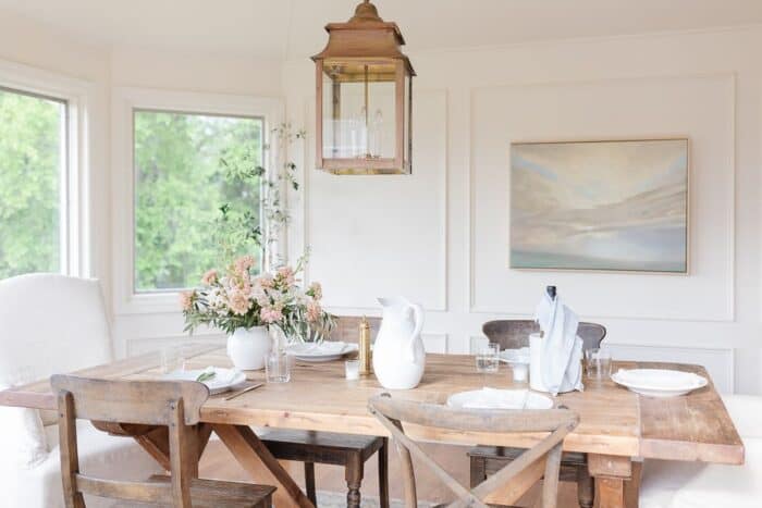 白色的餐厅里摆着农家乐的桌椅，上面挂着一盏黄铜灯笼。