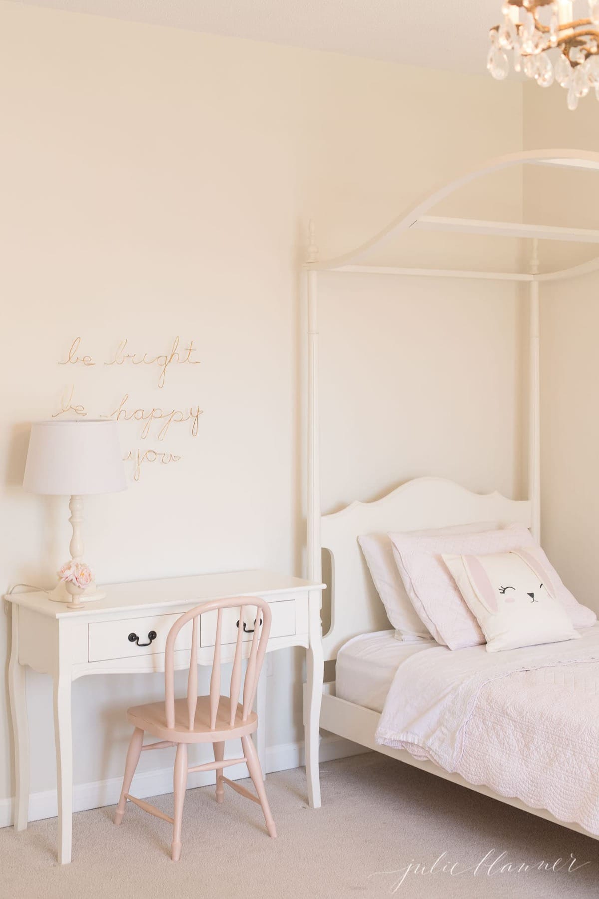 一间白色的女孩卧室和带顶篷的床，床头柜上涂着家具漆。