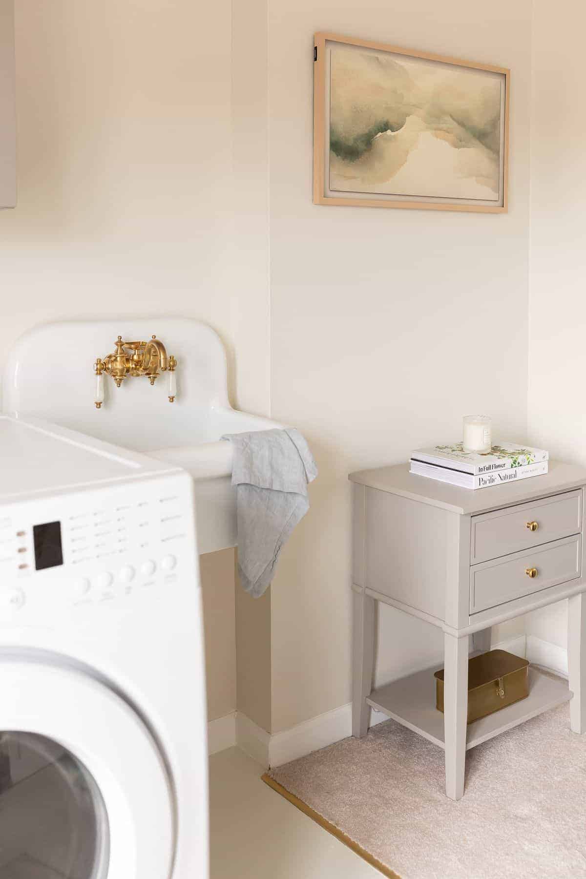 洗衣间里有一个白色的小水槽，一个边桌和几个用家具漆过的柜子