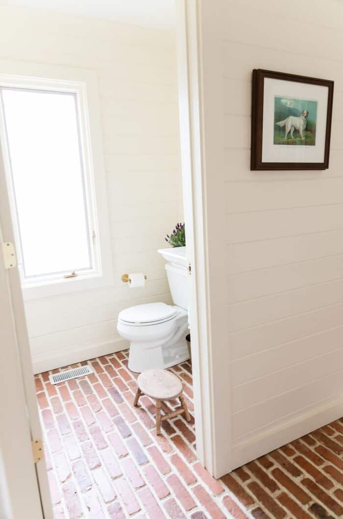 一间配有水平雪松镶板和砖地板的客用浴室。