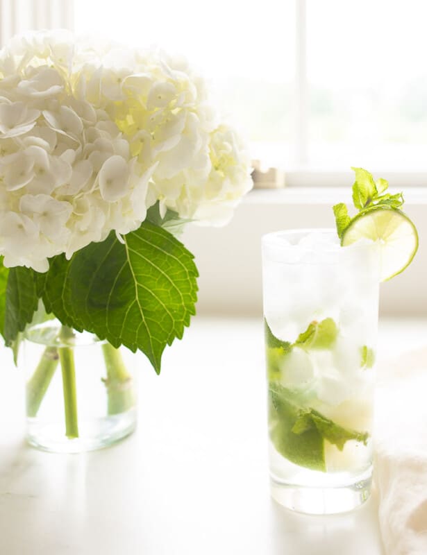 白色台面配有绣球花瓶和带有莫吉托的高大透明玻璃。