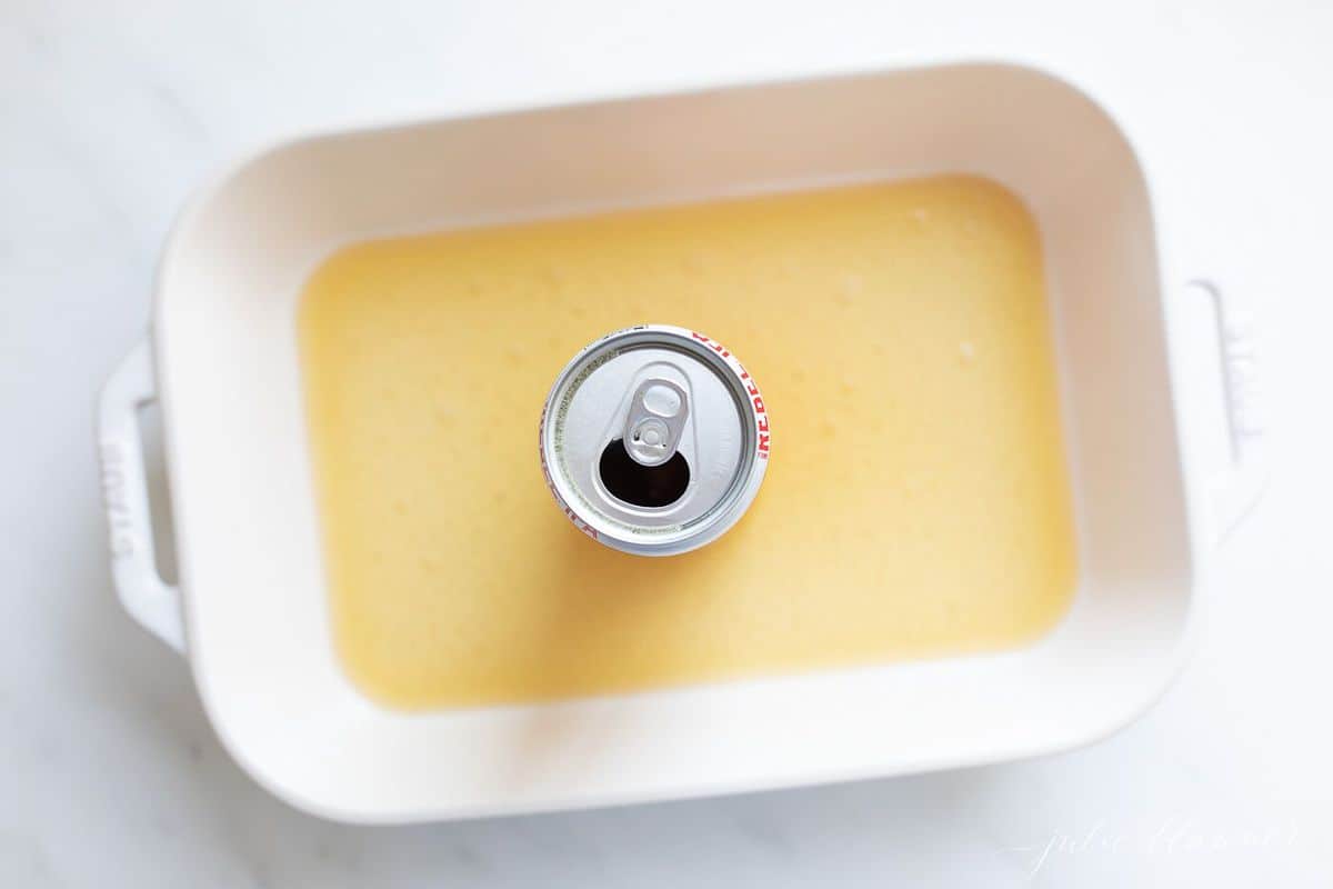 啤酒罐在一个白色的烤盘里，啤酒在锅底，在一个白色的表面。gydF4y2Ba