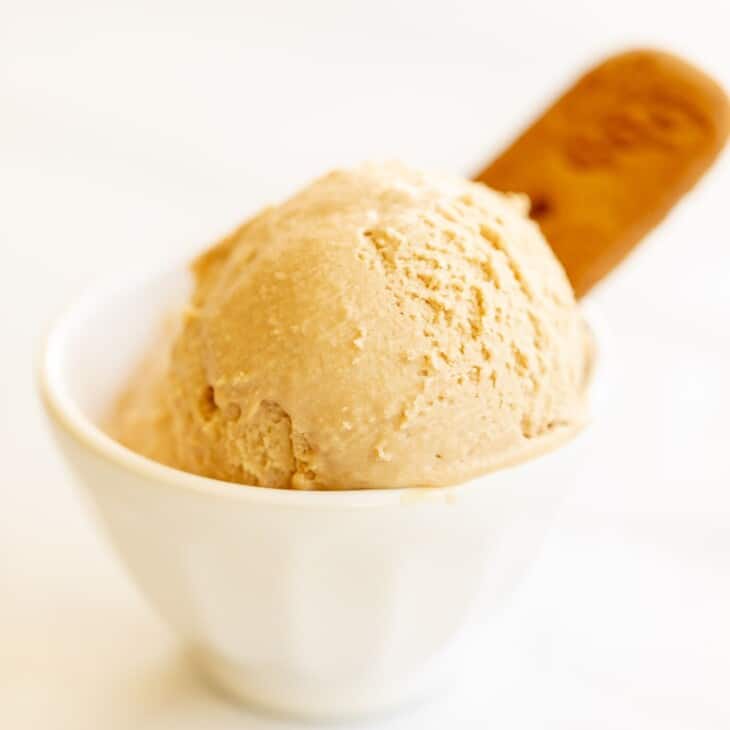 有曲奇饼黄油冰淇凌的两瓢的白色碗，在白色表面上。#cookiebuttericecream #speculoosicreamGydF4y2Ba