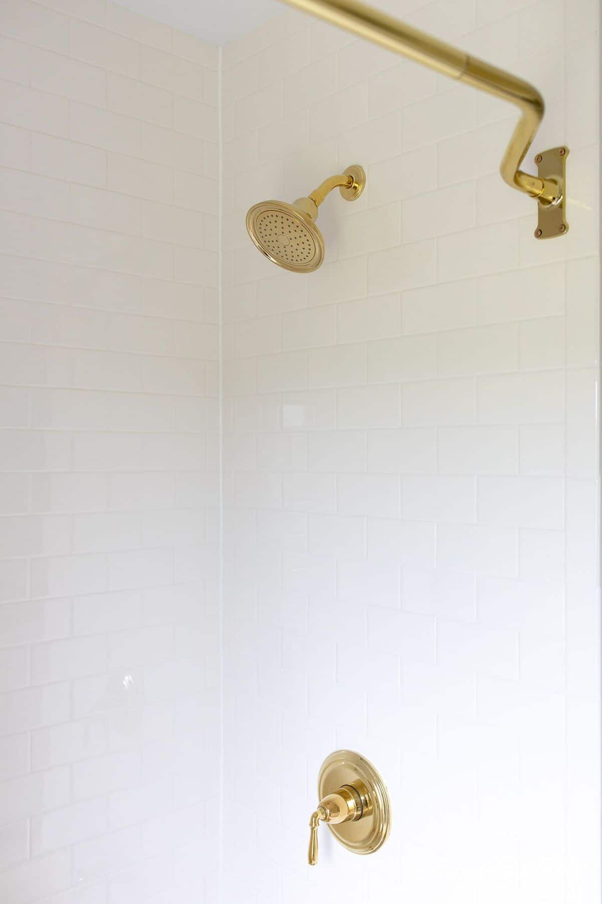 白色地铁瓷砖淋浴，黄铜淋浴头和浴缸装置。