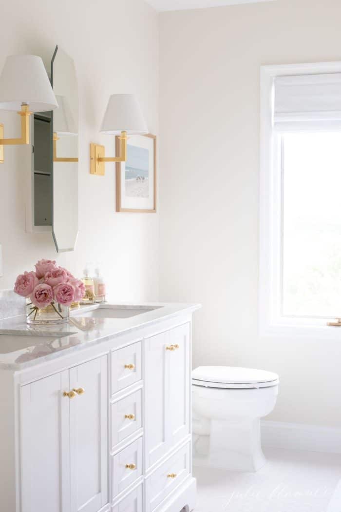 带有金色触摸的白色浴室，镜面的药柜略微ajar。#spabath