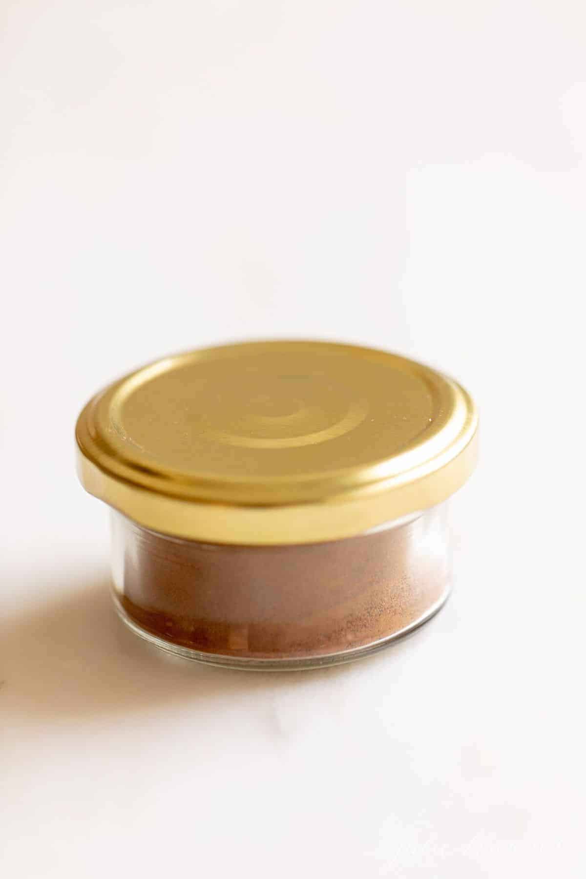 透明的香料罐，金色的盖子，放在白色的台面上。gydF4y2Ba