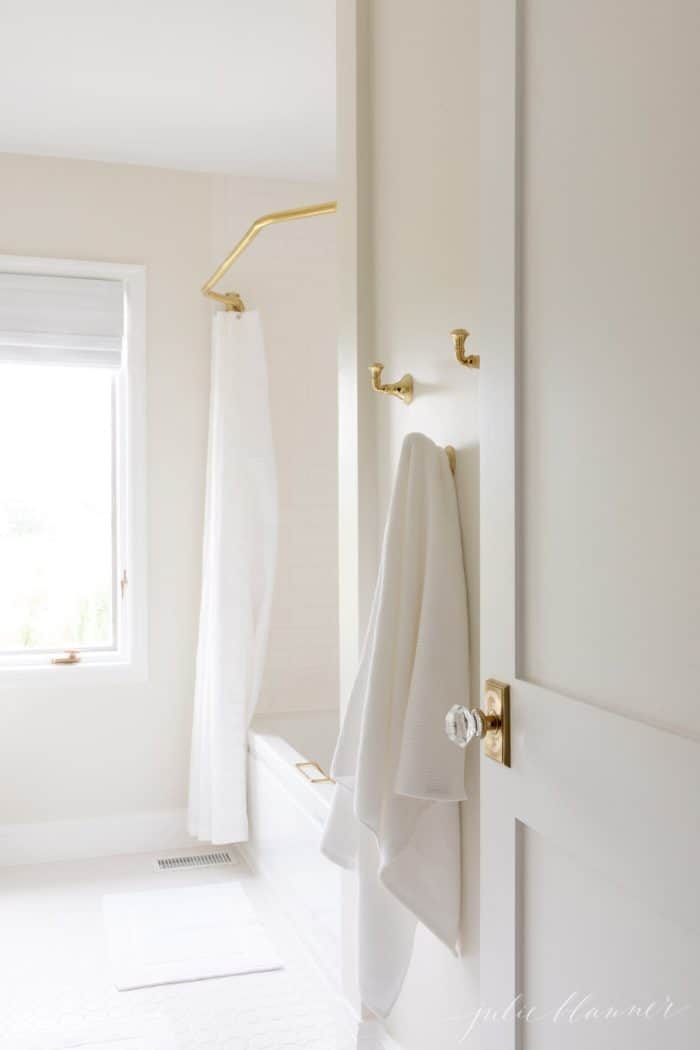 白色的浴室镜头，带有黄铜钩和黄铜浴帘。