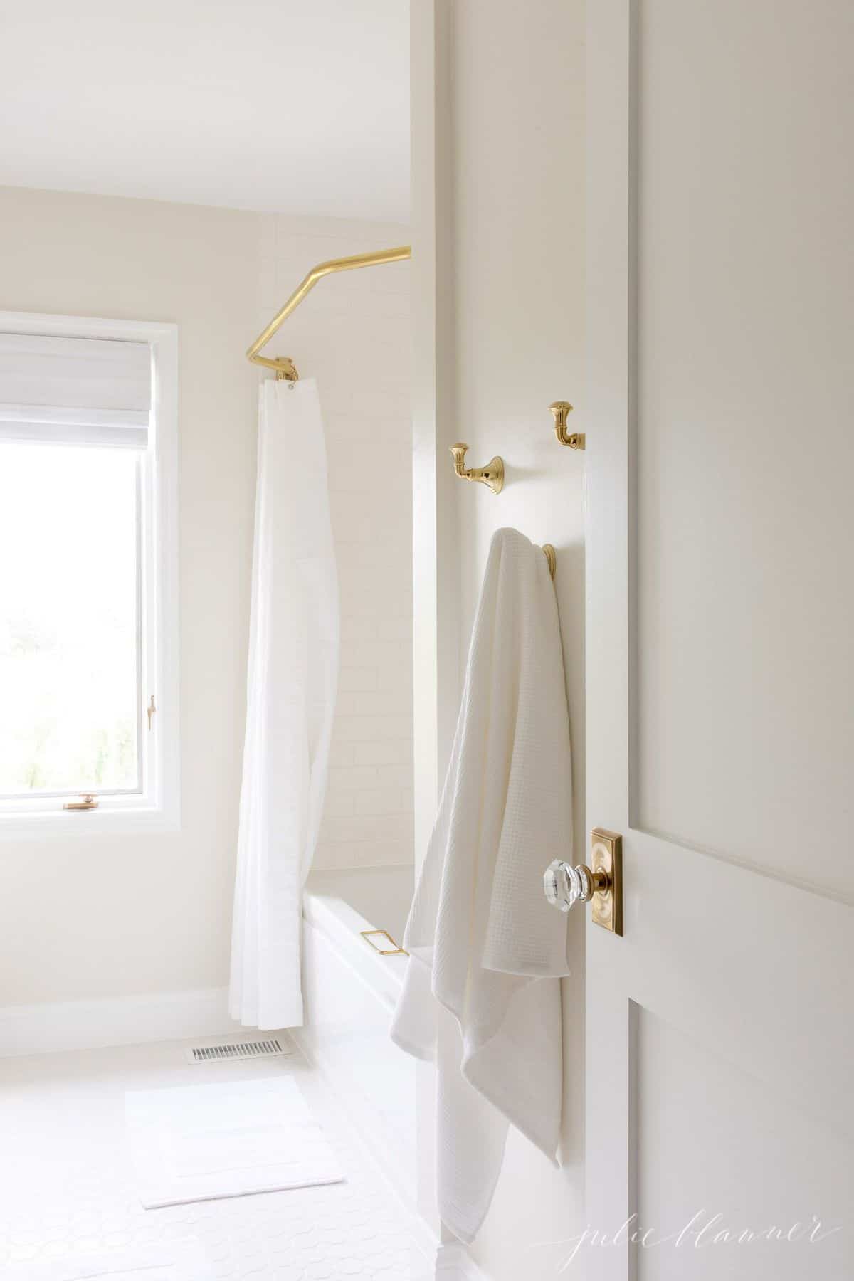 白色浴室镜头，有黄铜挂钩和黄铜浴帘杆。