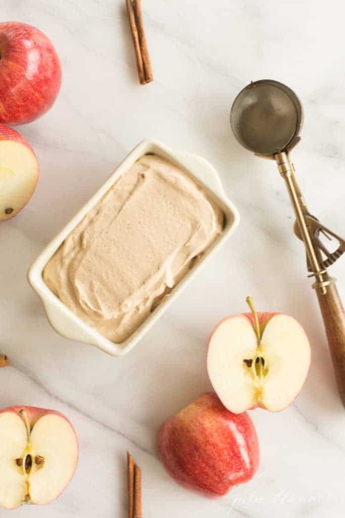 大理石表面放一盘苹果冰淇淋——冰淇淋勺和苹果片放在一边。