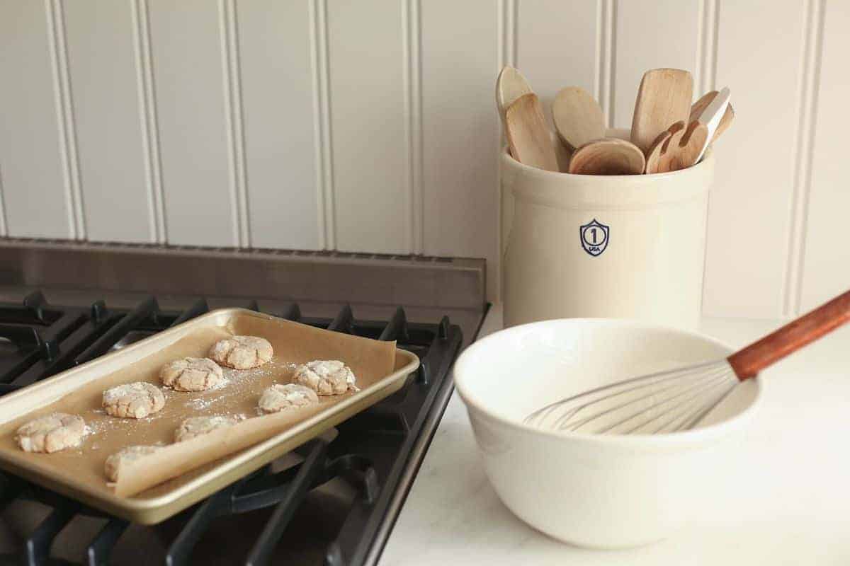 把一盘苹果饼干放在烤盘上，搅拌碗和勺子放在旁边的瓦罐里。