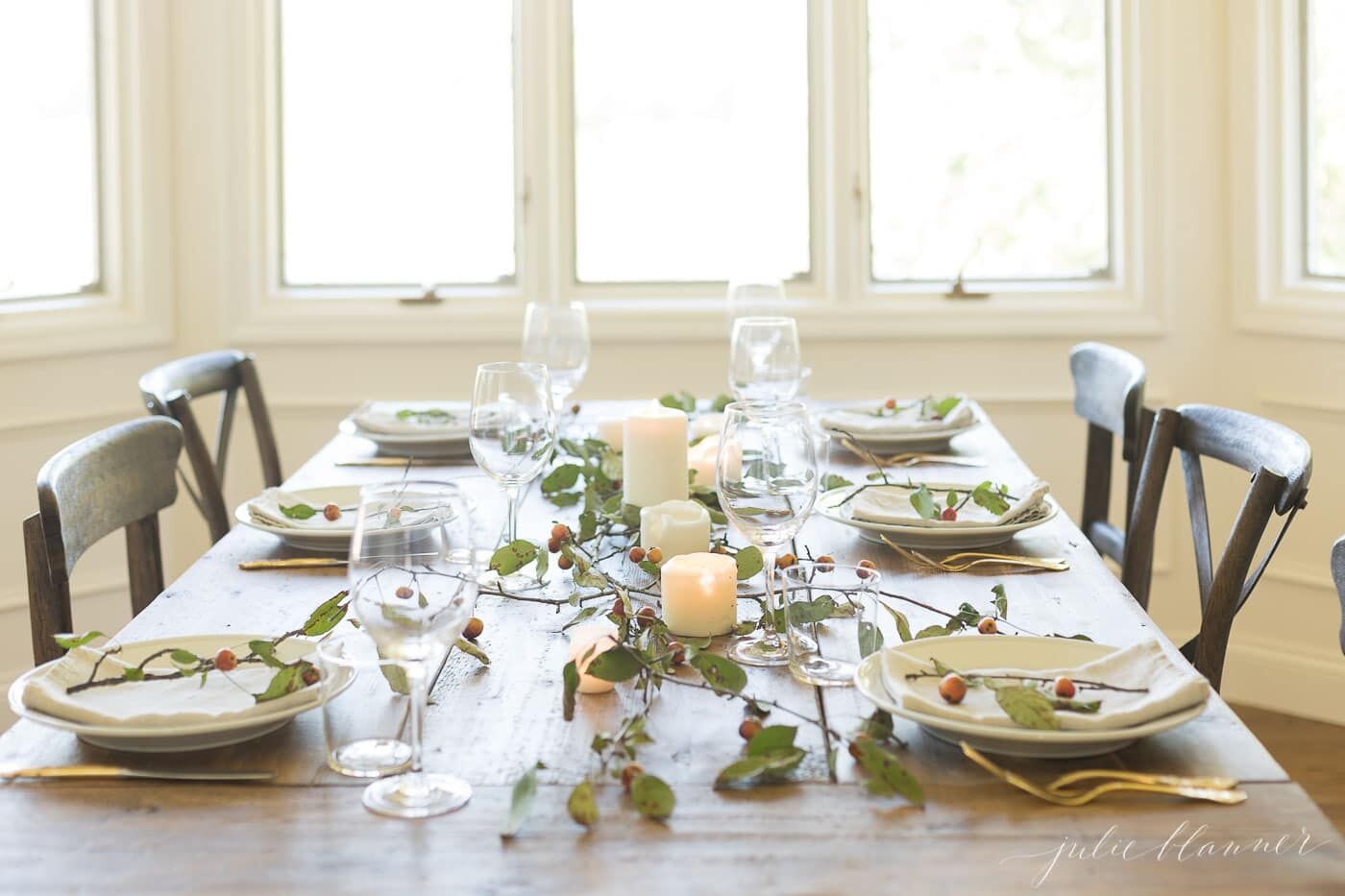 农场餐桌上摆放着感恩节晚餐，蜡烛和树枝在中间。