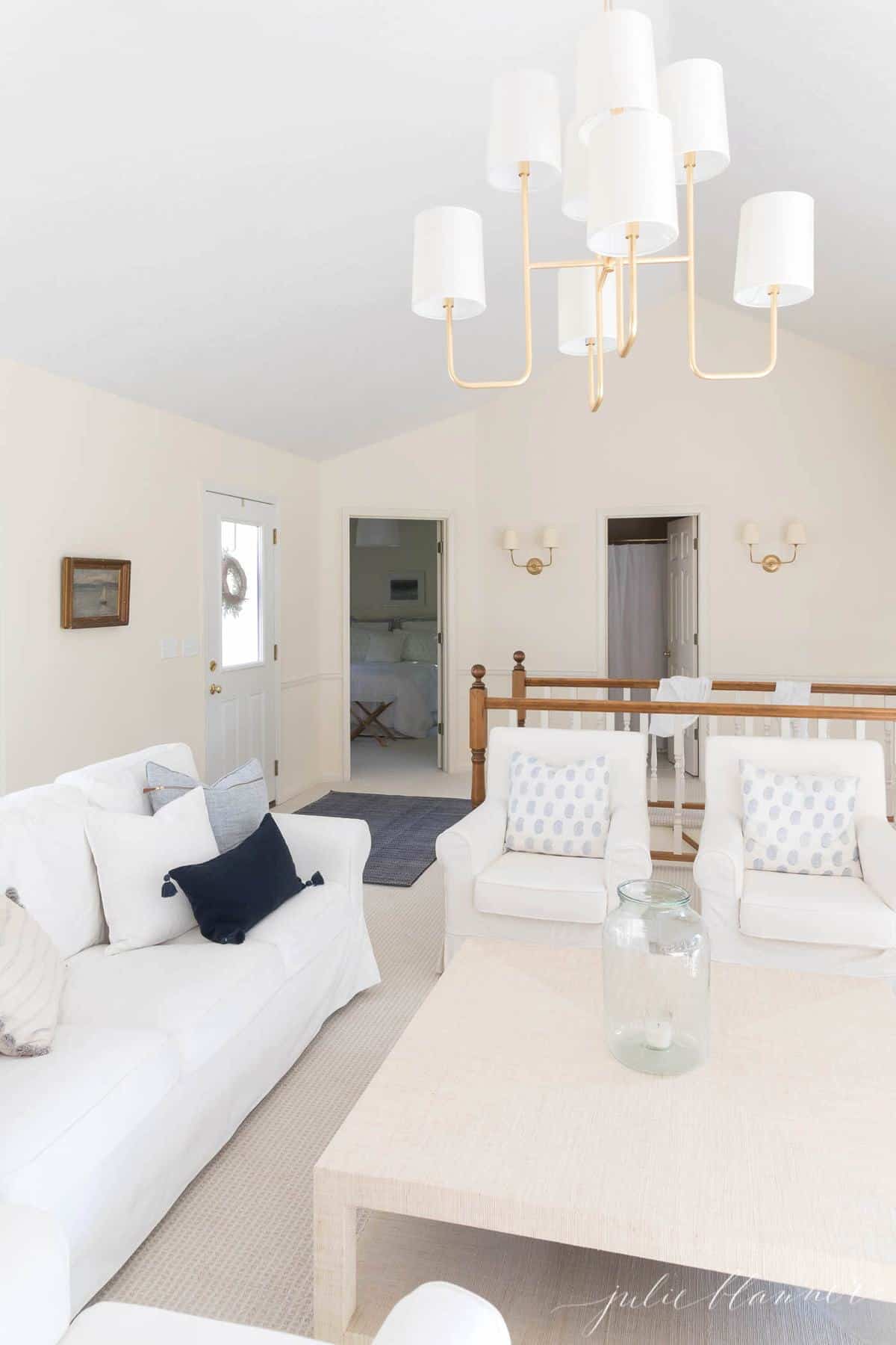 白色客厅，带有白色沙发和大米色咖啡桌，上面的黄铜吊灯。