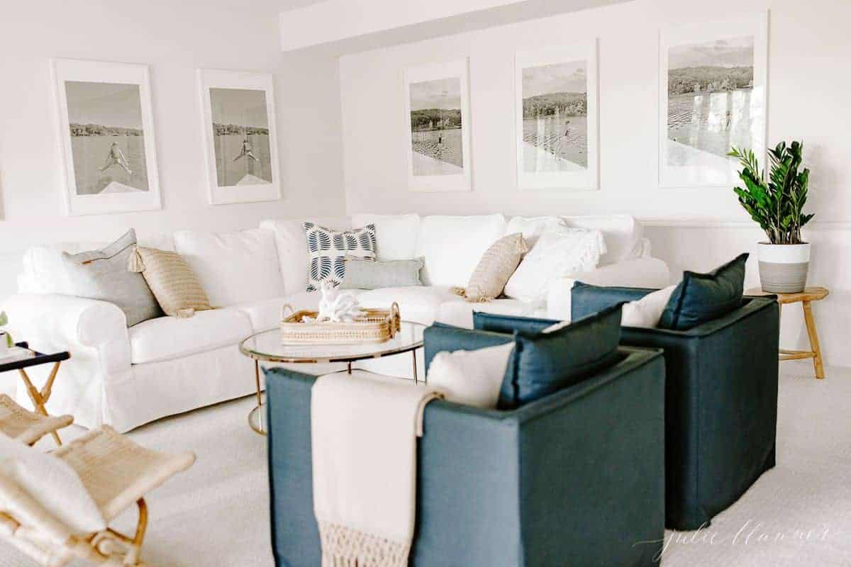 白色客厅，白色沙发，玻璃咖啡桌和一双海军蓝色椅子。