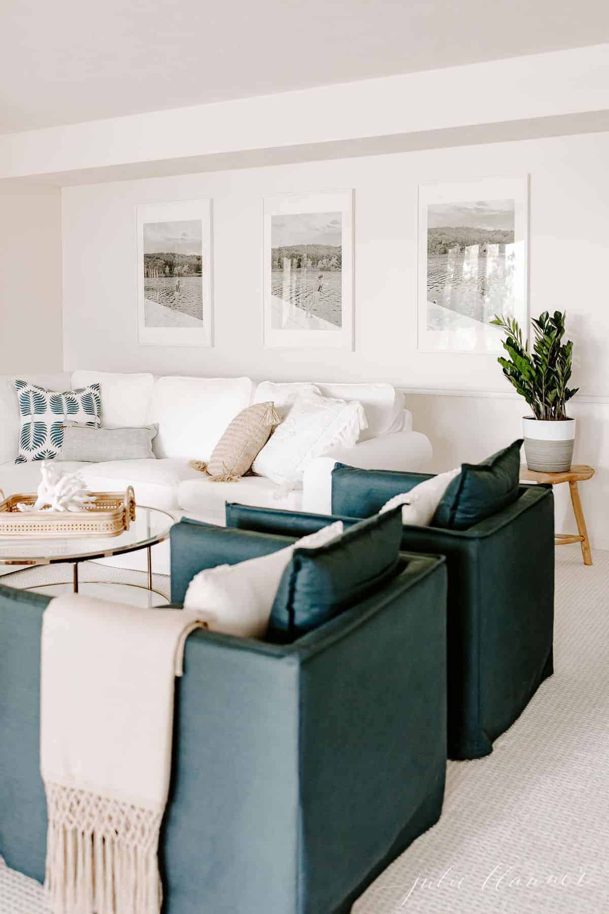 白色客厅，白色沙发，玻璃咖啡桌和一双海军蓝色椅子。