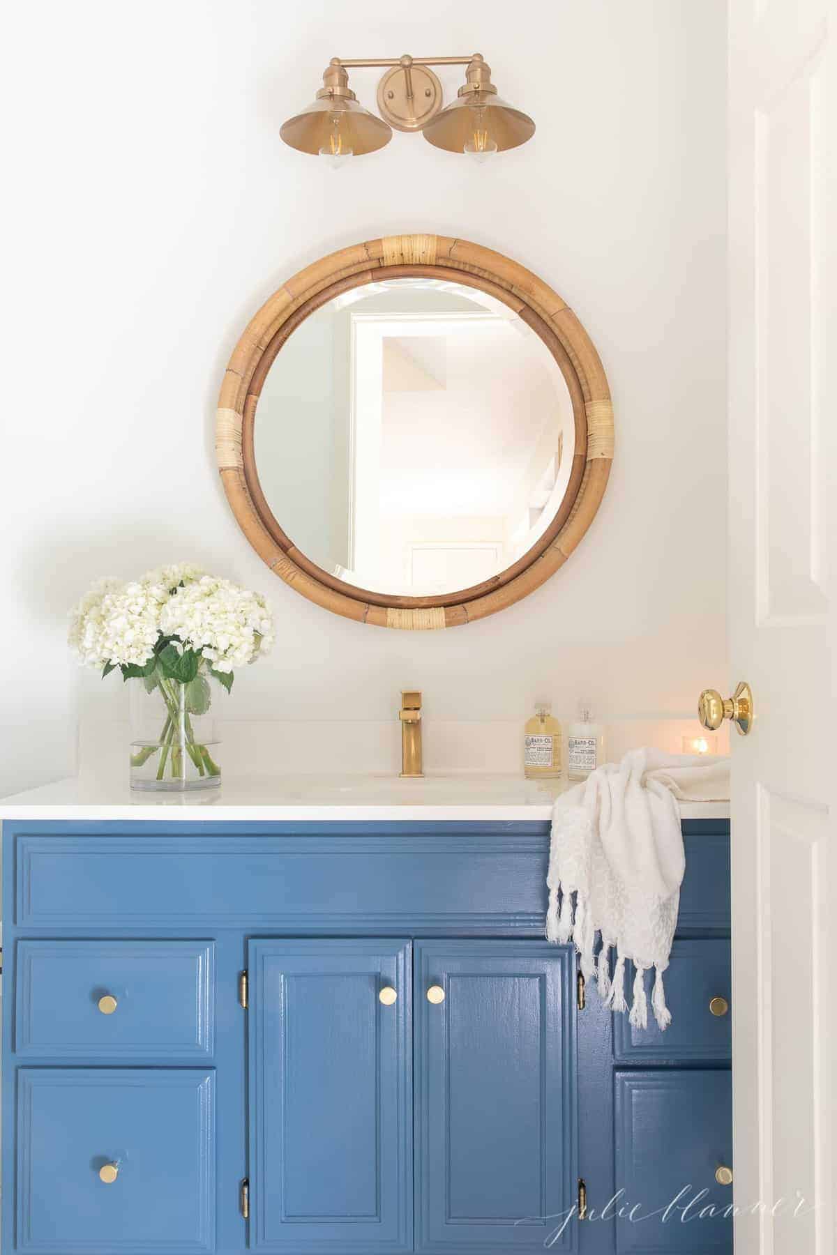 航海浴室，蓝色虚荣黄铜水龙头，圆藤镜子，鲜花和手巾