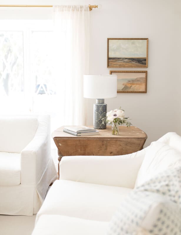 白色陶器谷仓覆盖的沙发，古董木桌，带蓝色的灯和简单的装饰。
