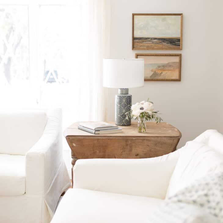白色Pottery Barn沙发套，古董木桌，蓝色台灯和简单的装饰在客厅里。