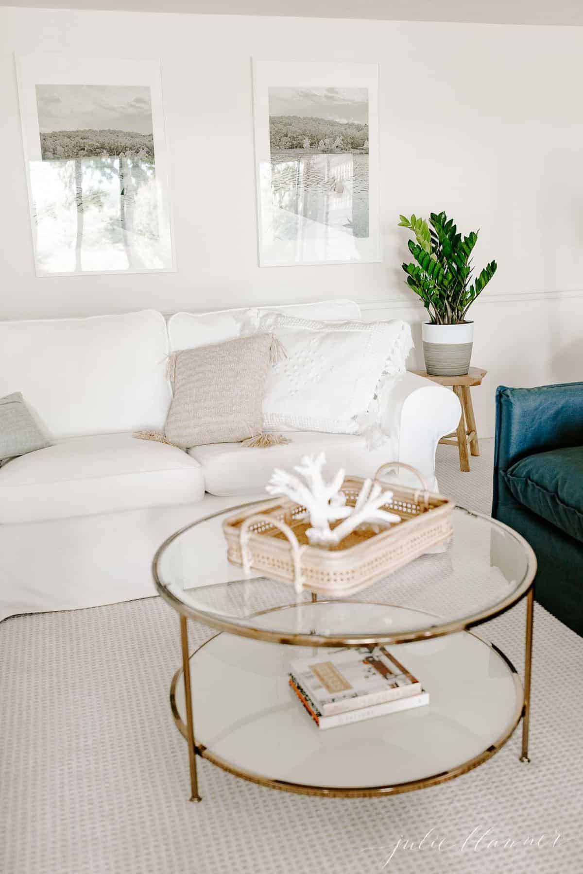 白色的客厅，白色的组合沙发，枕头，和一个玻璃和黄铜咖啡桌。