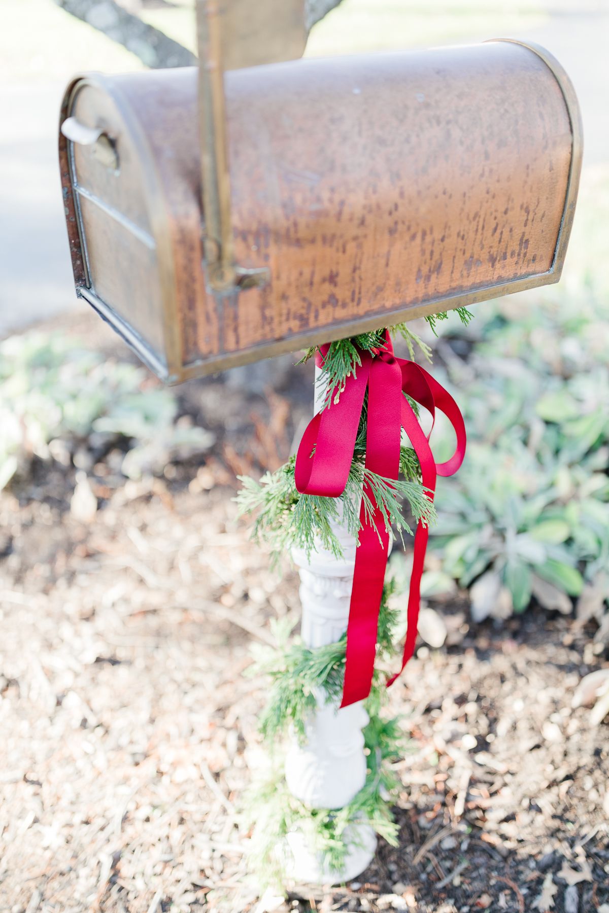 一个铜邮筒，用雪松花环和红色蝴蝶结装饰圣诞邮筒。