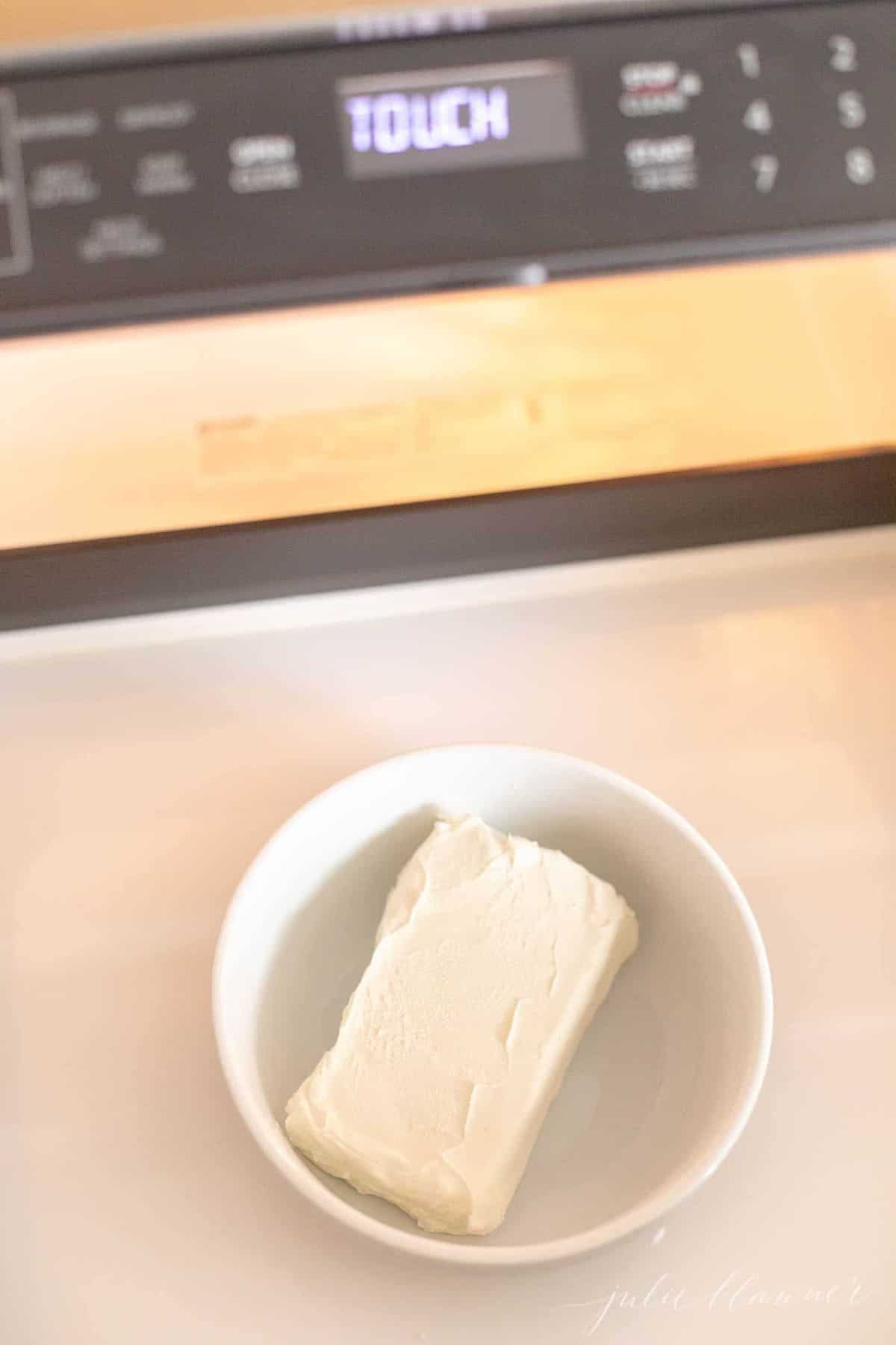 台面有一个白色的碗，里面有一块奶油奶酪。