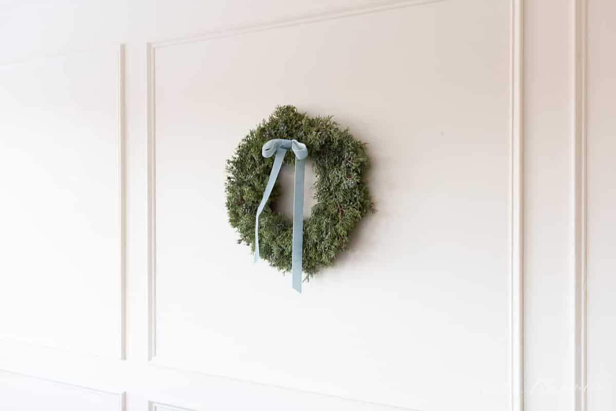 杜松的圣诞花圈，带有天鹅绒丝带悬挂在墙上