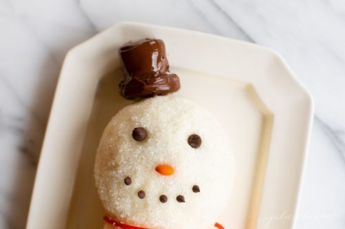 白色的表面，雪人芝士球在一个盘子，巧克力片微笑，巧克力棉花糖帽子。gydF4y2Ba