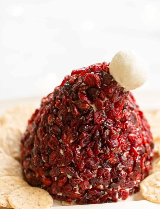 圣诞老人帽子形状的蔓越莓奶酪球在盘子上搭配饼干