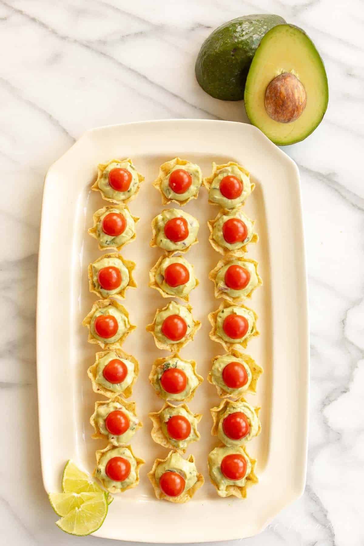 一盘装满薯片的拼盘，作为鳄梨沙拉，上面放一片樱桃番茄，牛油果放在一边。
