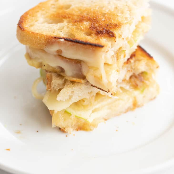 白色盘子，上面有切片和堆叠的美味烤奶酪三明治。