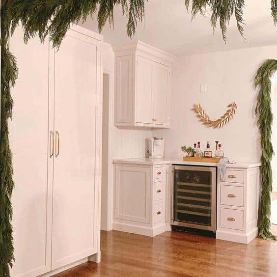 新厨房装饰有圣诞绿色植物，白色橱柜和木地板。