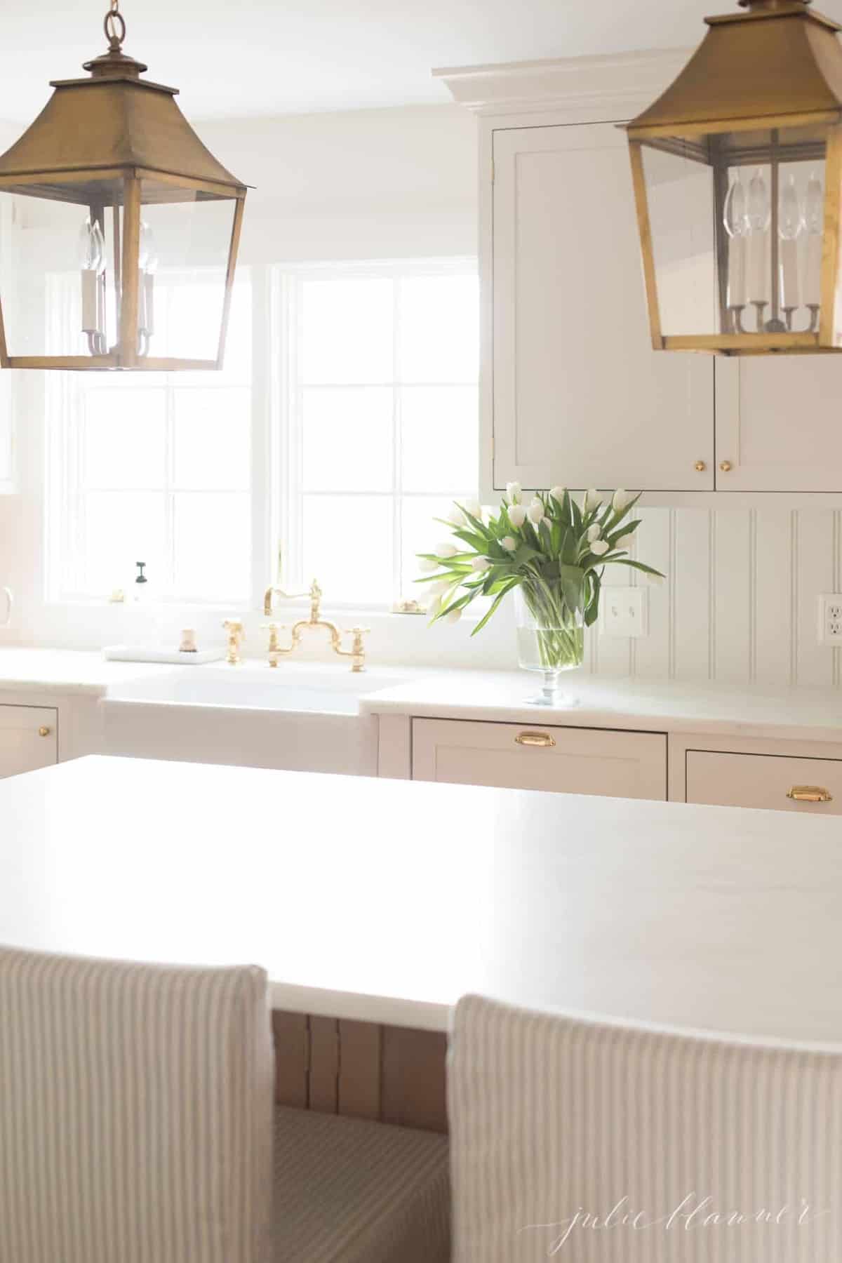 白色极简主义厨房，柜台上放着一个郁金香花瓶。