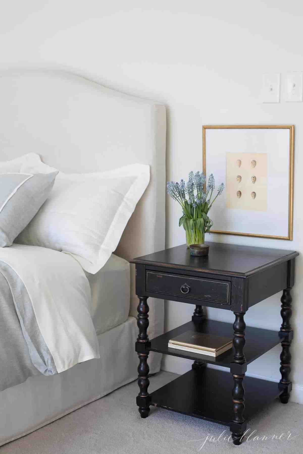 白色的卧室与装饰的花瓶花和弹簧在墙上的艺术品。