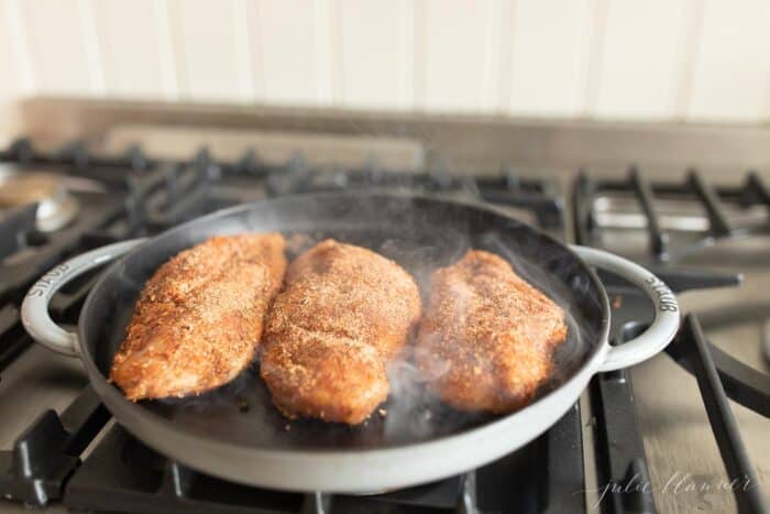 炉子上有一个铸铁锅，上面有三个烧黑的鸡胸肉。gydF4y2Ba