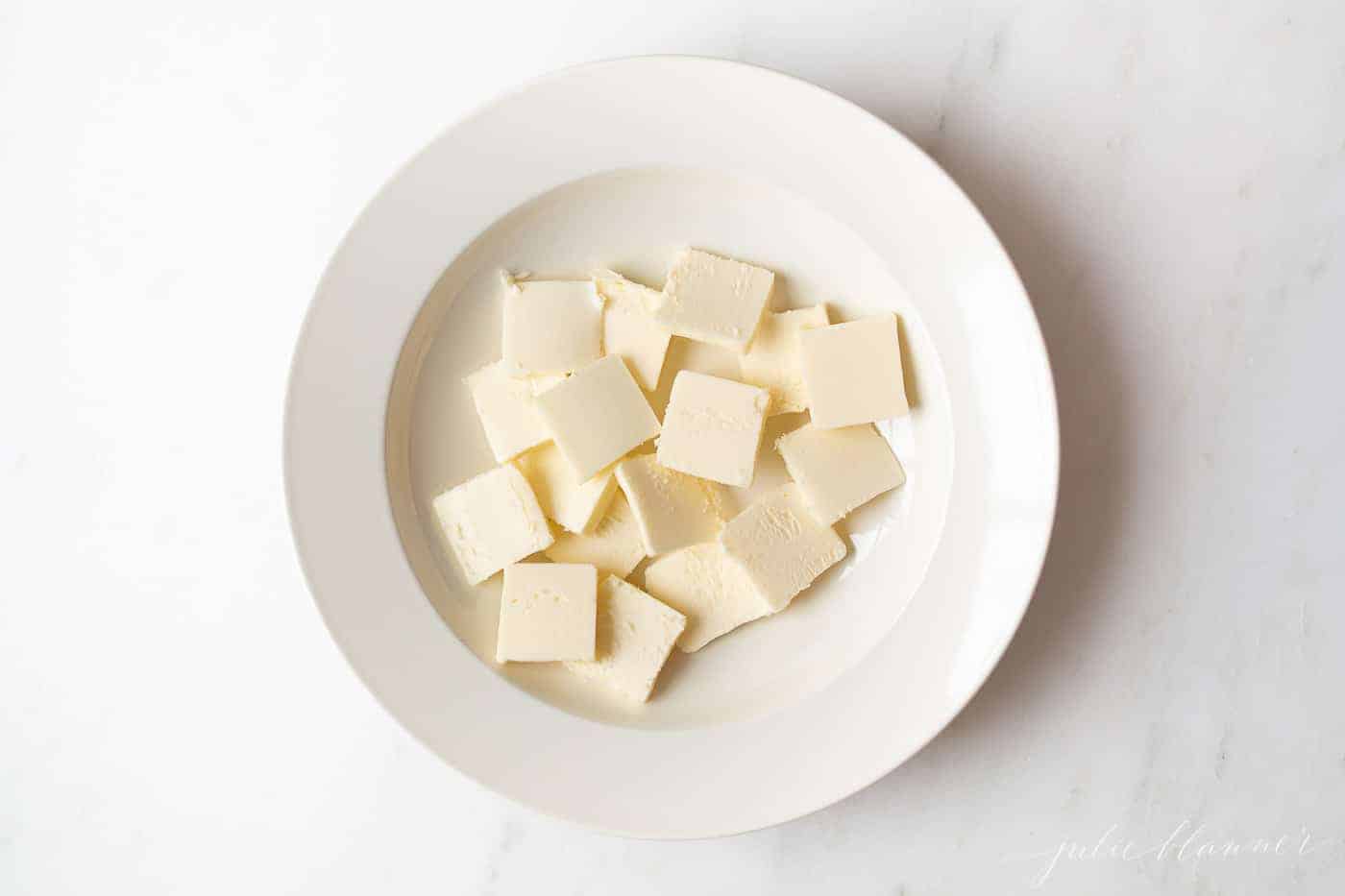 白色的表面，白色的盘子里装满了切好的冷黄油。gydF4y2Ba