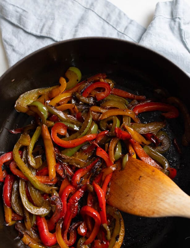 铸铁锅里满炒的甜椒，木勺到侧面。