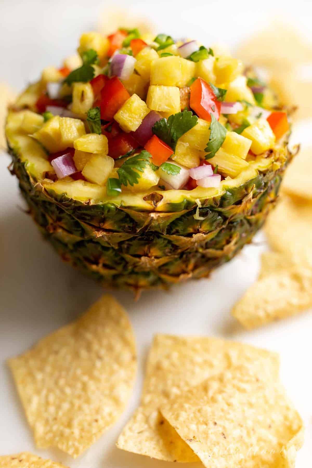 用切好的菠萝做成的新鲜的碗，里面塞满了菠萝沙司，周围是墨西哥玉米片。