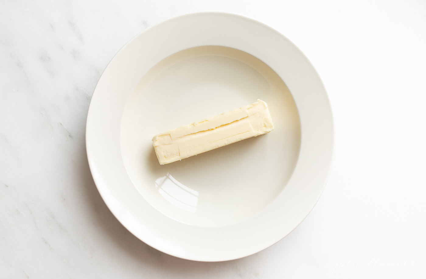 白色的盘子放在白色的表面上，中间放一根黄油。gydF4y2Ba