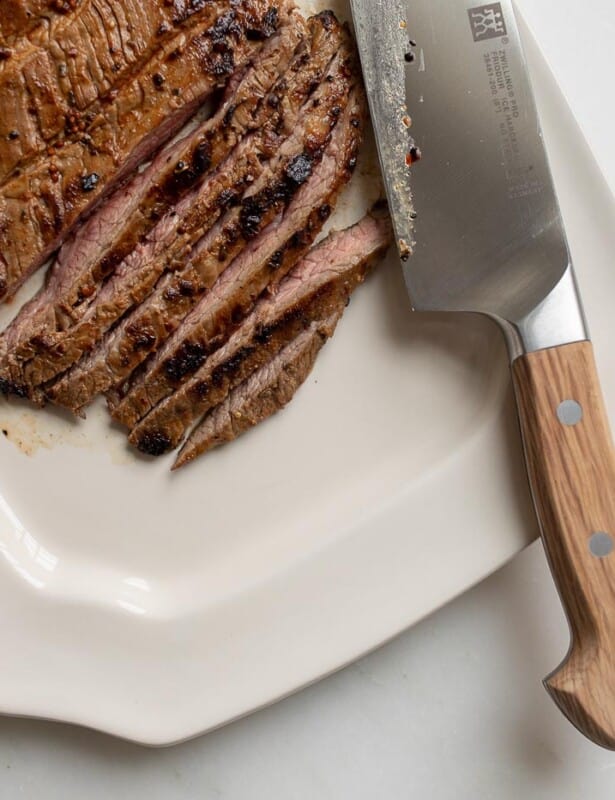 白色盘子和切成薄片的卡恩·阿萨达（Carne Asada），刀到侧面