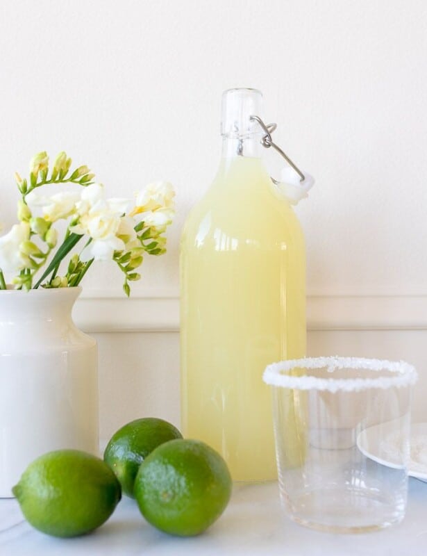 白色厨房背景，充满自制玛格丽塔酒的玻璃玻璃水瓶，酸橙侧面。