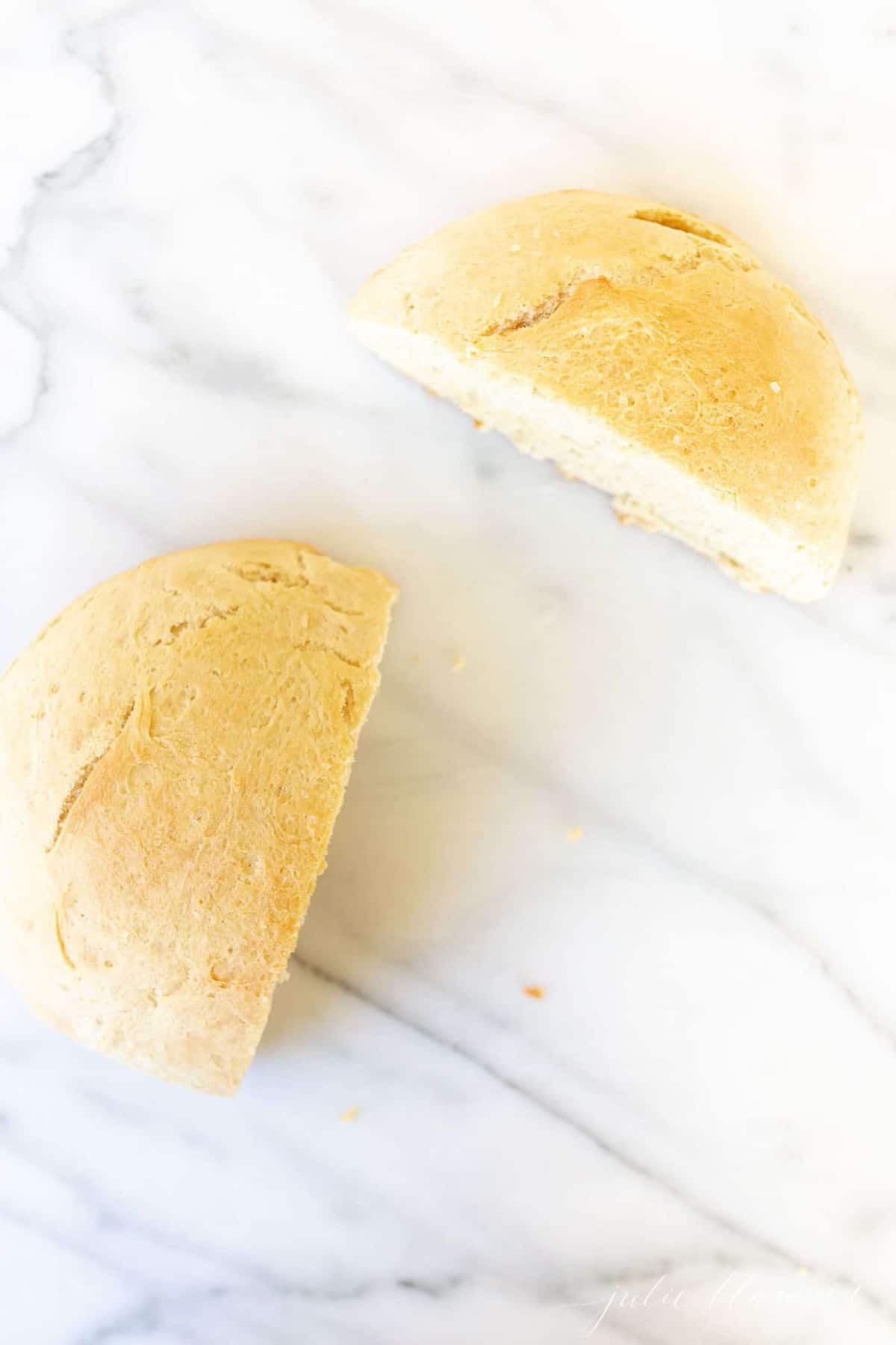 一条用酵母烘烤的圆形自制面包，将大理石表面切成两半。