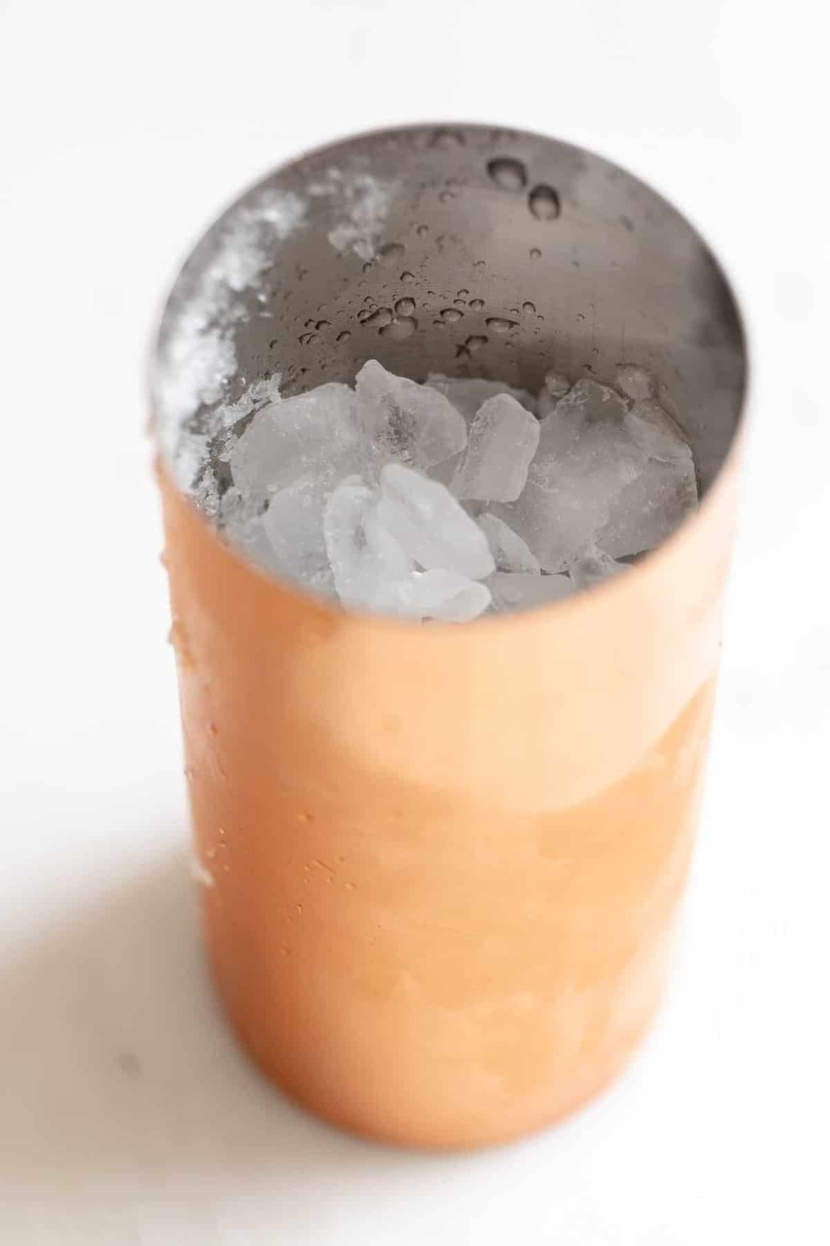 白色表面，铜鸡尾酒搅拌器装满了冰。