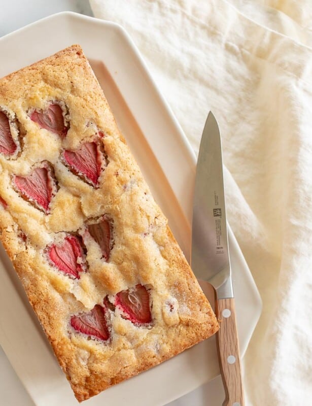 象牙盘，上面有一条新鲜的草莓面包，刀到侧面。