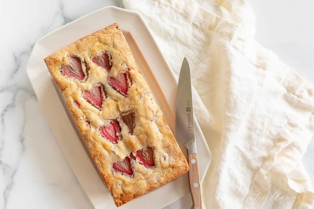 草莓面包放在白盘子里，旁边放着一把刀和亚麻餐巾。gydF4y2Ba